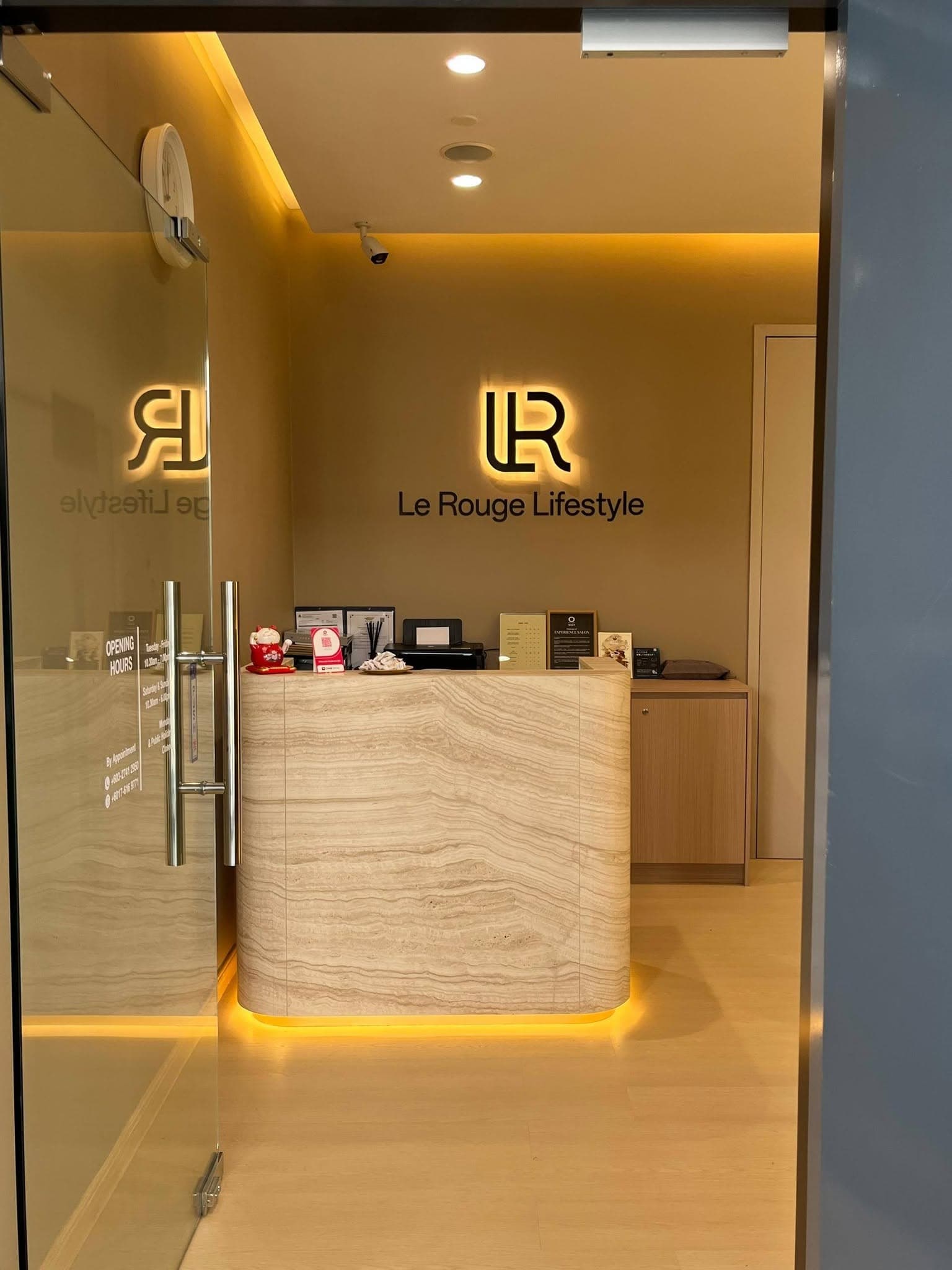 Le Rouge Lifestyle reception with backlit LR monogram and travertine desk